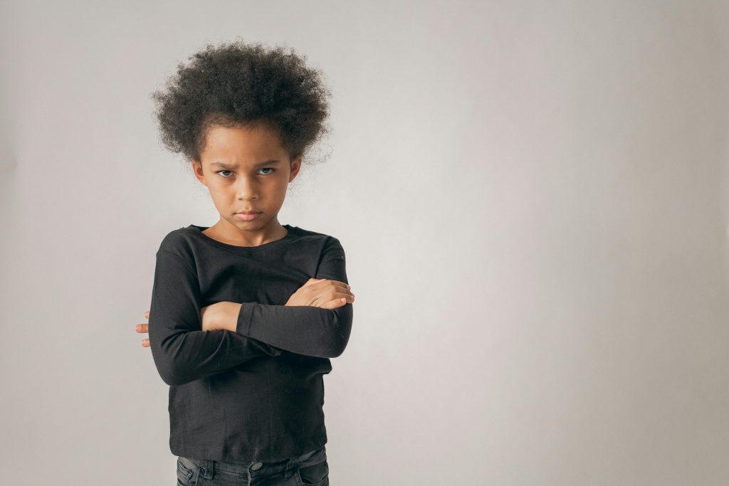 young child looking unhappy with arms crossed